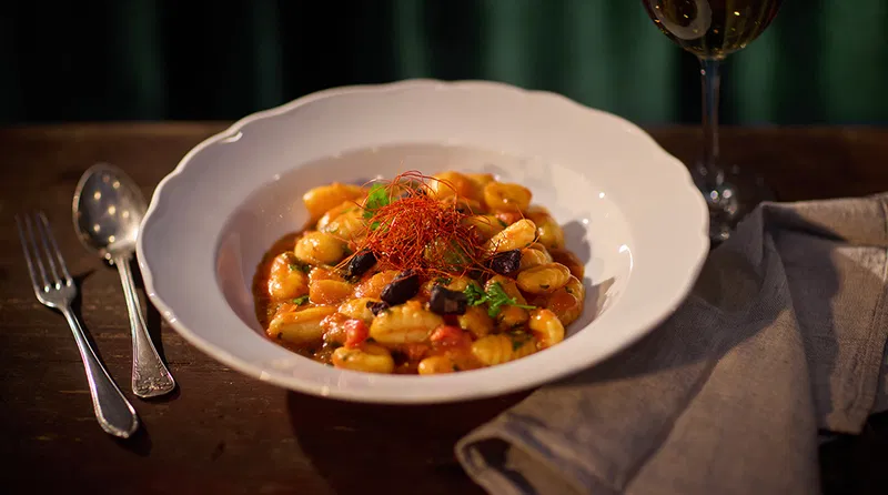 Gnocchi puttanesca tomaattikastikkeessa syvällä lautasella