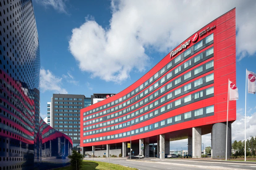Punainen rakennus, jossa on paljon ikkunoita ja jonka oikeassa yläkulmassa on Sokos Hotel Flamingon logo